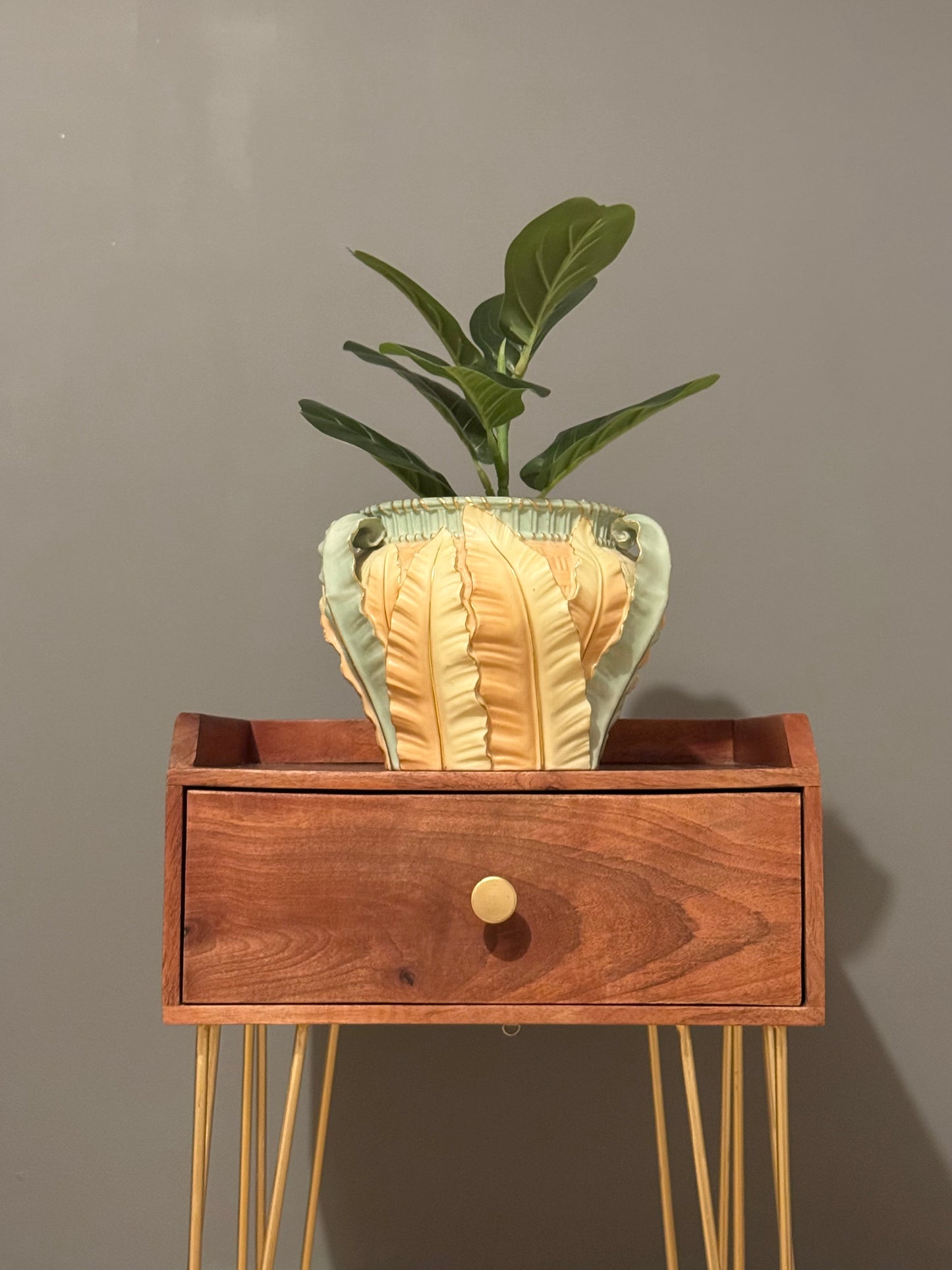 This antique Royal Worcester blush ivory jardinière features exquisite leaf decorations in stunning pastel colors of yellow, green, orange, and gold. It is adorned with three green leaf-shaped handles extending from the base to the rim, accented with gold highlights. Royal Worcester is a name synonymous with luxury and exquisite craftsmanship in the world of fine porcelain. Established in 1751, the company is one of the oldest and most revered porcelain manufacturers in England, with a rich history that sp