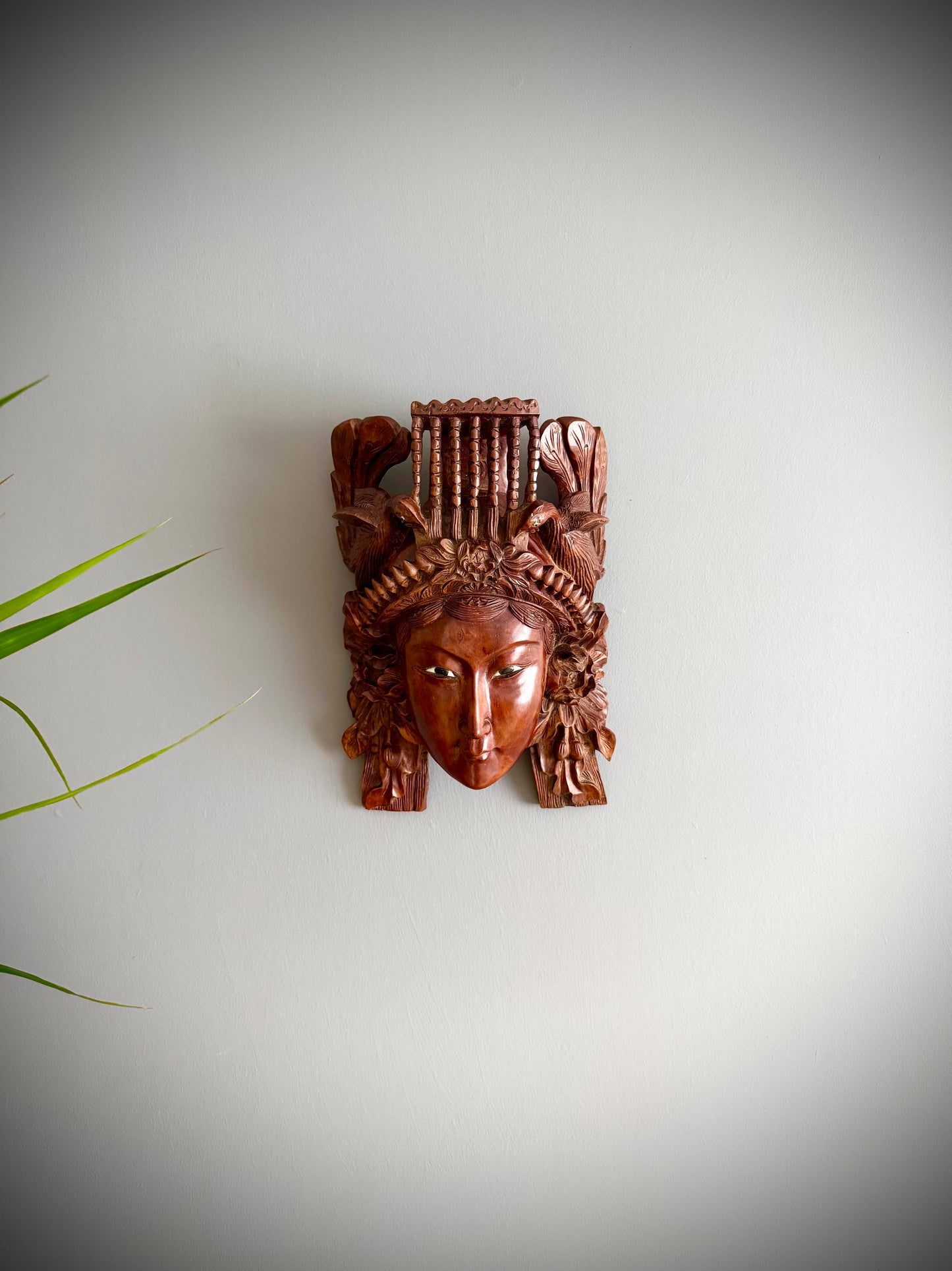 This intricately detailed Chinese carved rosewood mask is truly captivating. The mask showcases a crown with a flaming pearl above a lotus flower, also flanked by two beautifully carved peacocks. The mask is enhanced with inset glass and enamel eyes. Remarkably, the mask retain its original eyes, and the wood is intact, which is very rare. the mask is mounted with a hanging bracket, the craftsmanship in the rosewood carving is absolutely exquisite.