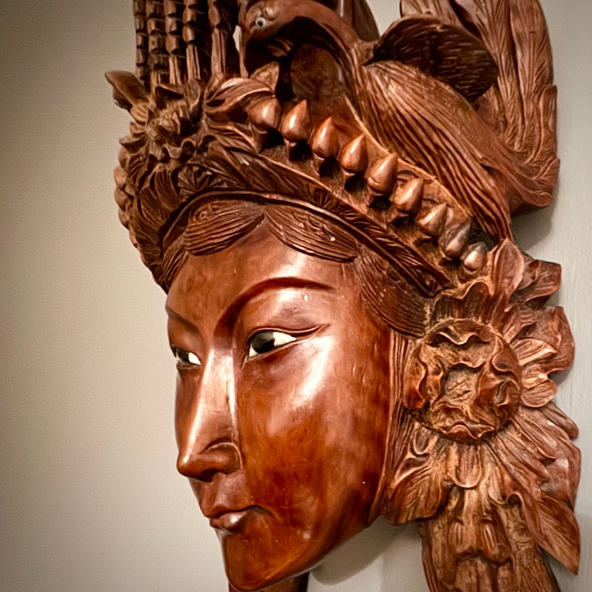 This intricately detailed Chinese carved rosewood mask is truly captivating.&nbsp; The mask showcases a crown with a flaming pearl above a lotus flower, also flanked by two beautifully carved peacocks. The mask is enhanced with inset glass and enamel eyes. Remarkably, the mask retain its original eyes, and the wood is intact, which is very rare. the mask is mounted with a hanging bracket, the craftsmanship in the rosewood carving is absolutely exquisite.